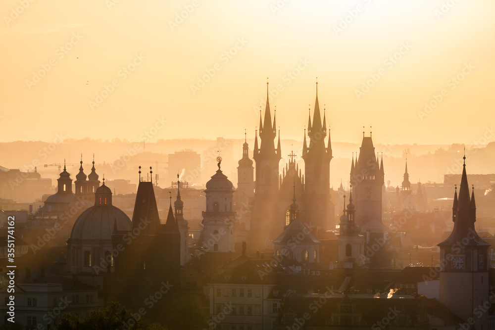 View of foggy Prague with Charles Bridge from Petrin hill view point in the early morning with sun rays coming through the fog. Silhouettes of temples, towers and buildings. Prague, Czech Republic.