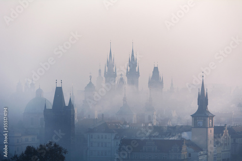 View of the centre of Prague and Charles bridge in the fog in the early morning with towers and silhouettes. Prague, Czech Republic