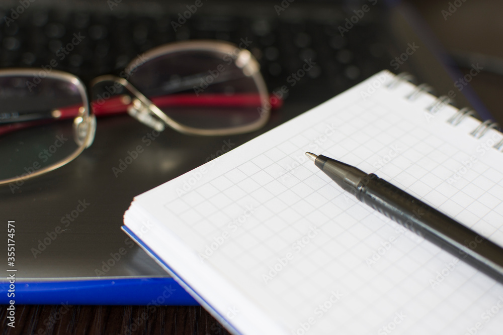 A blank notepad and a black pen laid next to two pink tulips. A blank notepad and a black pen laid next to two pink tulips.