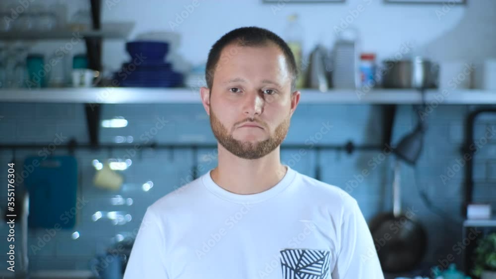Slow motion portrait of young man serious then smiling in cozy house looking at camera standing alone. People, positive emotions and lifestyle concept. Slow motion portrait of young man serious then smiling in cozy house looking at camera standing alone. People, positive emotions and lifestyle concept.