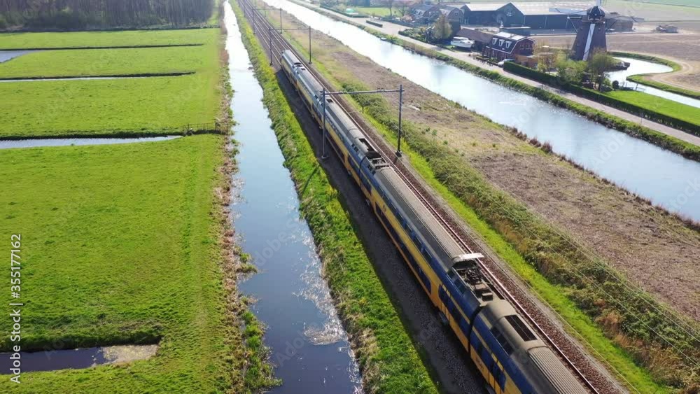 Aerial view of high speed train passing by traditional Dutch windmill, Netherlands, Holland