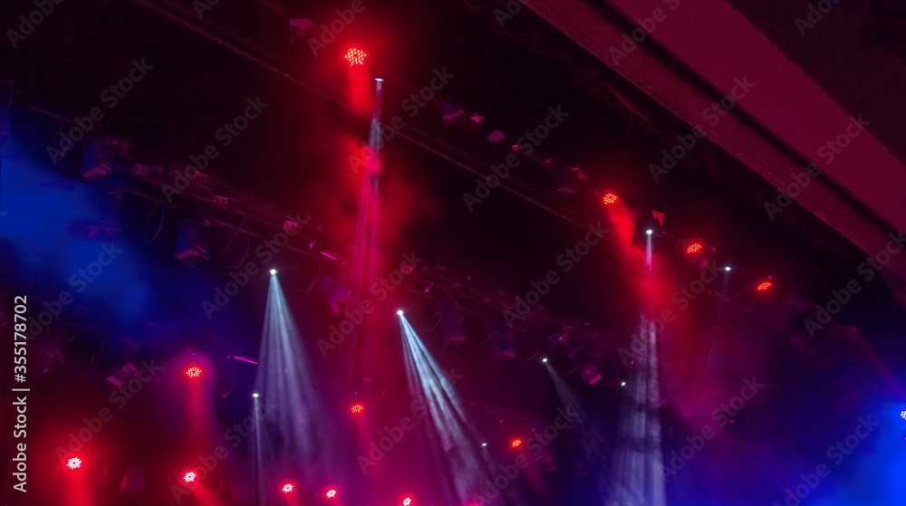 Stage lights. Several projectors in the dark. Multi-colored light beams from the stage spotlights on the stage in the smoke at the time of the entertainment show. Night club. Lights show. Lazer show