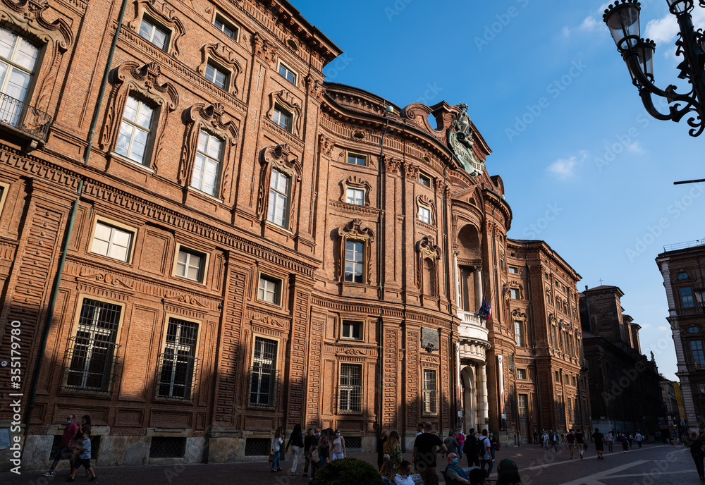 Obraz premium Turin, Piedmont, Italy. May 2020. Palazzo Carignano, an imposing Baroque palace, it has a red brick facade characterized by wavy shapes. People wear the mask to protect themselves from the coronavirus
