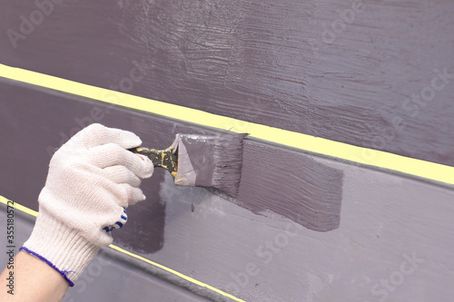 Painting of a wooden back of a swing with a brush of lilac paint