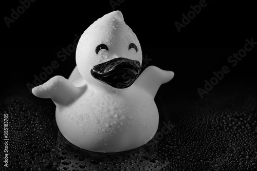 Rubber duck toy on a reflective surface covered with water droplets in black & white