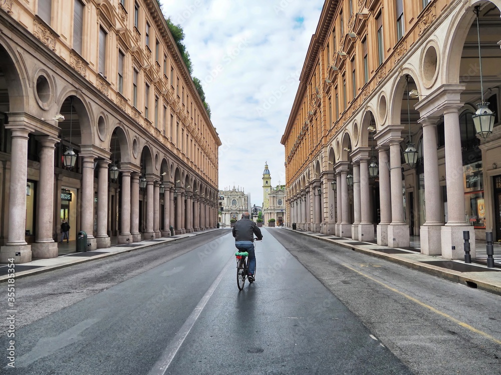 Aged man biking in deserted city for nationwide lockdown caused by Coronavirus epidemic emergency narrow foreground focus Turin Italy May 4 2020