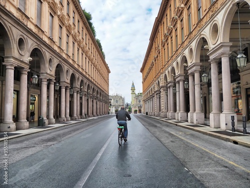Aged man biking in deserted city for nationwide lockdown caused by Coronavirus epidemic emergency narrow foreground focus Turin Italy May 4 2020 © antomar