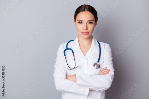 Photo of attractive serious family doctor doc virologist not smiling experienced skilled professional arms crossed wear medical gown lab coat stethoscope isolated grey background