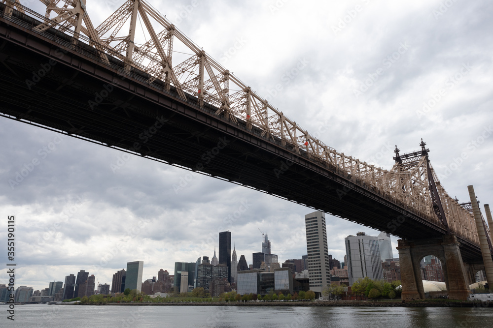 Queensboro Bridge along the East River with the Midtown Manhattan Skyline in New York City on a Cloudy Day Queensboro Bridge along the East River with the Midtown Manhattan Skyline in New York City on a Cloudy Day