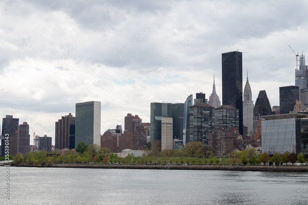 Midtown Manhattan Skyline along the East River in New York City with a Cloudy Sky Midtown Manhattan Skyline along the East River in New York City with a Cloudy Sky