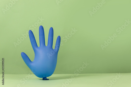 Принти на полотні Latex inflated rubber glove inflated like balloons on a green background
