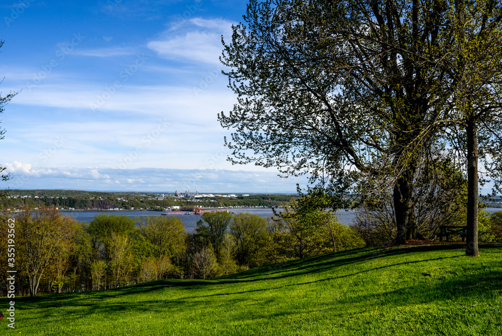 Overview of Quebec, Canada and St Lawrence River, from grassy hill with trees in Battlefields Park. Overview of Quebec, Canada and St Lawrence River, from grassy hill with trees in Battlefields Park.