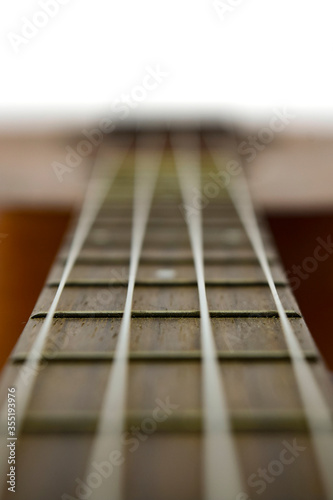 The neck of a traditional ukulele guitar. Ukulele with white nylon strings on isolated white background.