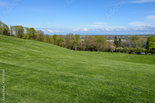 Rolling grassy hills in Battlefields Park with blue sky and a view overlooking Quebec  Canada.