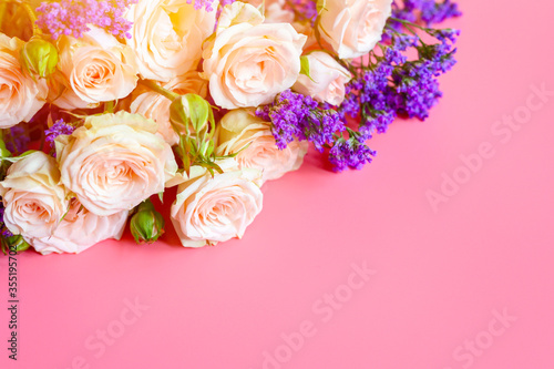 a bouquet of cream roses and bright purple flowers in full bloom on a pink background with space for text. greeting card. flare © Ksenia