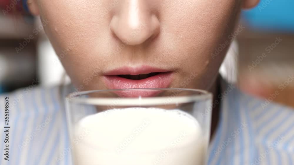 Woman is drinking milk. Female hand holds glass to his mouth and drinks milk Woman is drinking milk. Female hand holds glass to his mouth and drinks milk