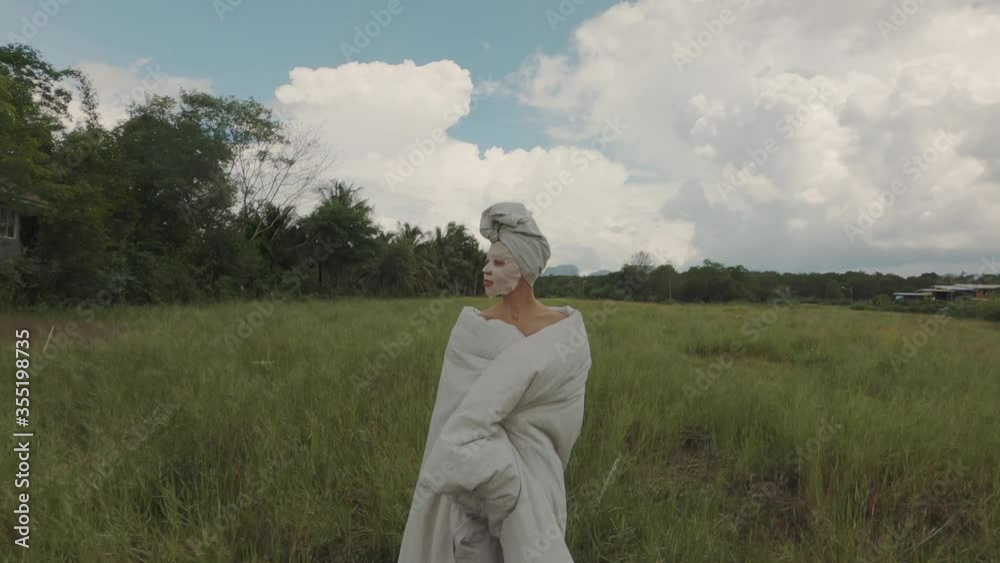 Girl in mask wrapped in a blanket and standing outdoors in the field Girl in mask wrapped in a blanket and standing outdoors in the field