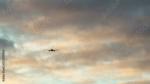 A passenger airliner takes off, in clouds at sunset.