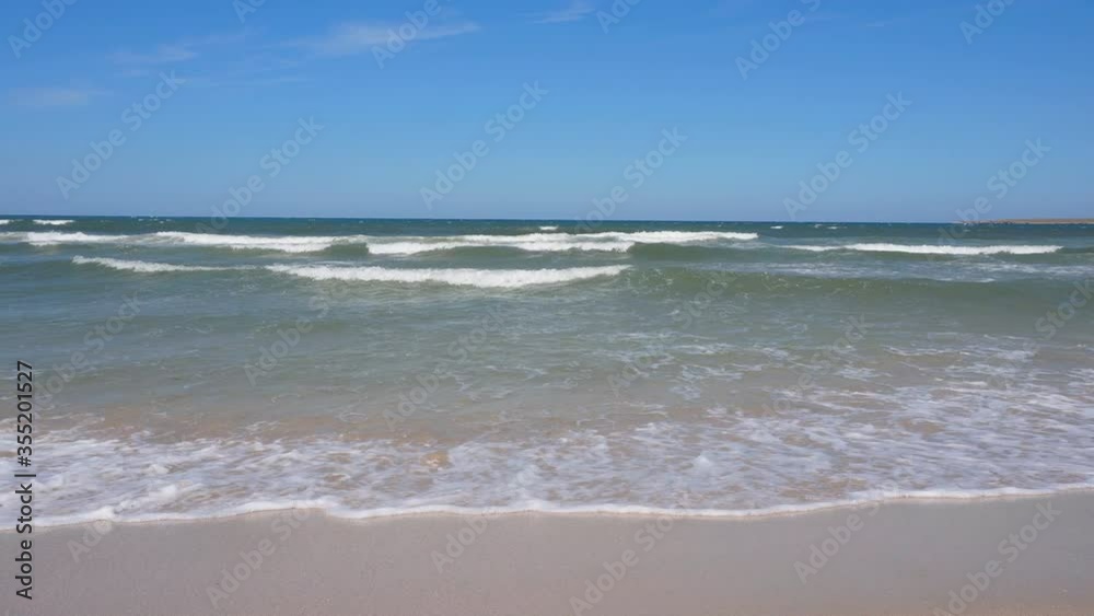 Beautiful waves on the shore of a sandy beach. Waves of turquoise water against a blue sky on a Sunny day. Beautiful waves on the shore of a sandy beach. Waves of turquoise water against a blue sky on a Sunny day.
