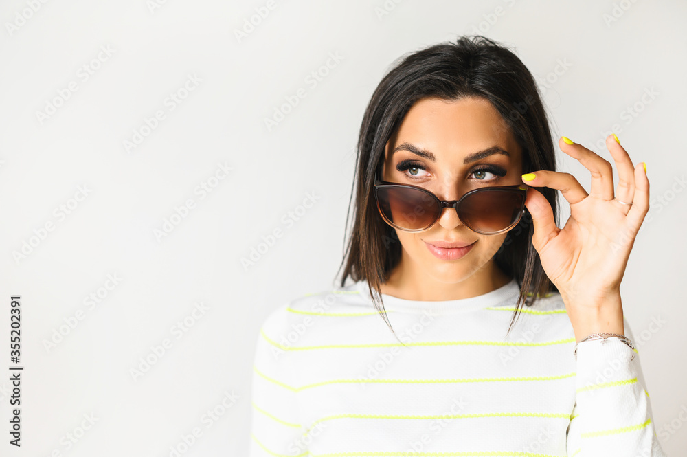 Close-up portrait of attractive brunette woman, she flirting and looks above sunglasses Close-up portrait of attractive brunette woman, she flirting and looks above sunglasses