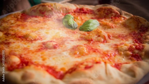 Cinemagraph of smoke emitted from a hot Italian pizza. The hot cheese is bubbling. Traditional Italian food. Close up, loop with selective focus.