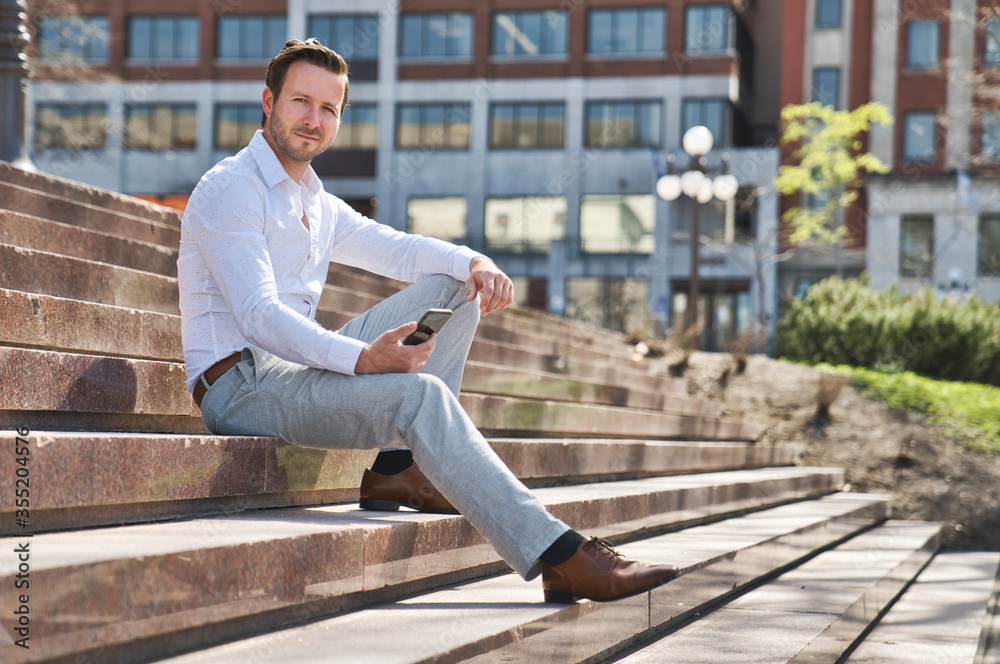 Obraz premium Portrait of an handsome man on the urban background holding phone