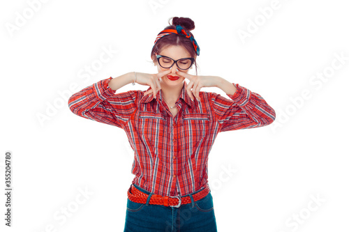 Displeased woman covers nose with hand, smells something awful