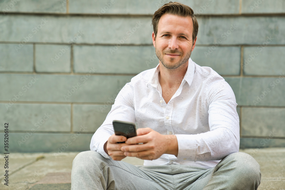 Obraz premium Portrait of an handsome man on the urban background holding phone