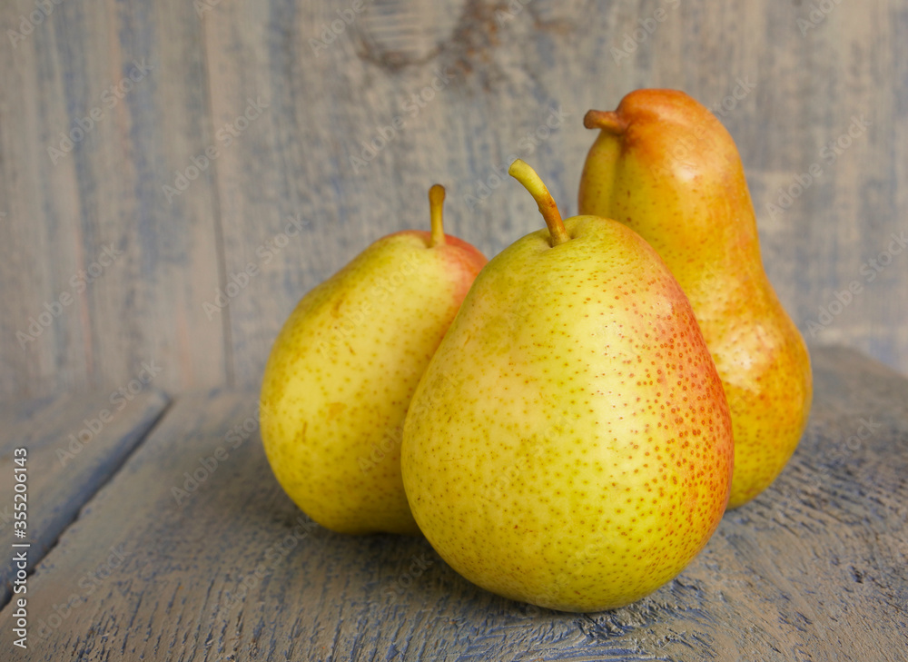 Three beautiful juicy ripe whole pears on a blue wooden background. Concept of a fruit diet Three beautiful juicy ripe whole pears on a blue wooden background. Concept of a fruit diet