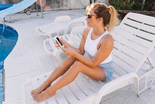 Woman sitting by the pool using her phone.