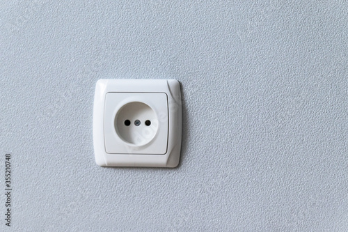 Electric socket mounted on grey wall at modern flat