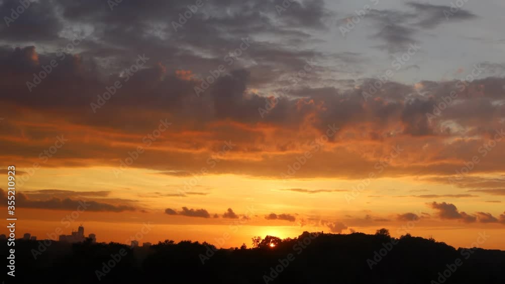 Time lapse of sunset with clouds and high rise building silhouettes on horizon Time lapse of sunset with clouds and high rise building silhouettes on horizon