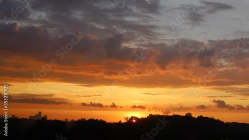 Time lapse of sunset with clouds and high rise building silhouettes on horizon 
