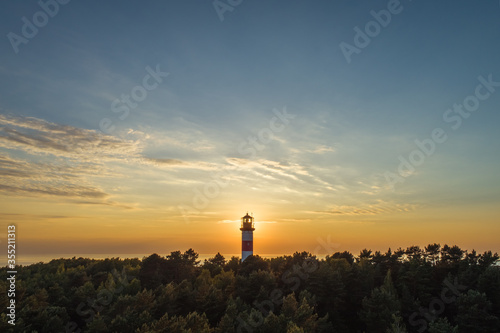 Evening sky aerial view of lighthouse surrounded by vegetation in Curonian spit near Nida, Lithuania