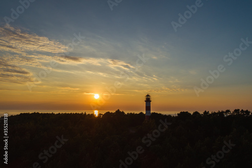 Silhouette of lighthouse surrounded by vegetation and evening sky background in Curonian spit near Nida, Lithuania