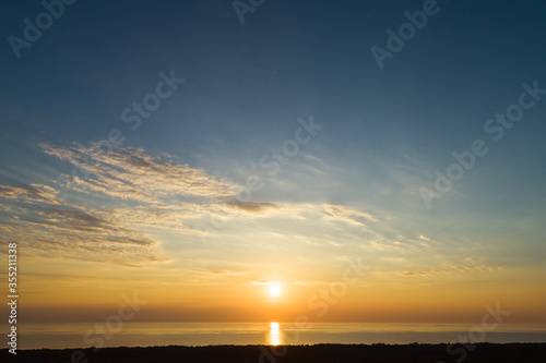 Sundown aerial view of evening sky with light clouds and sun descending to sea in Curonian spit near Nida  Lithuania
