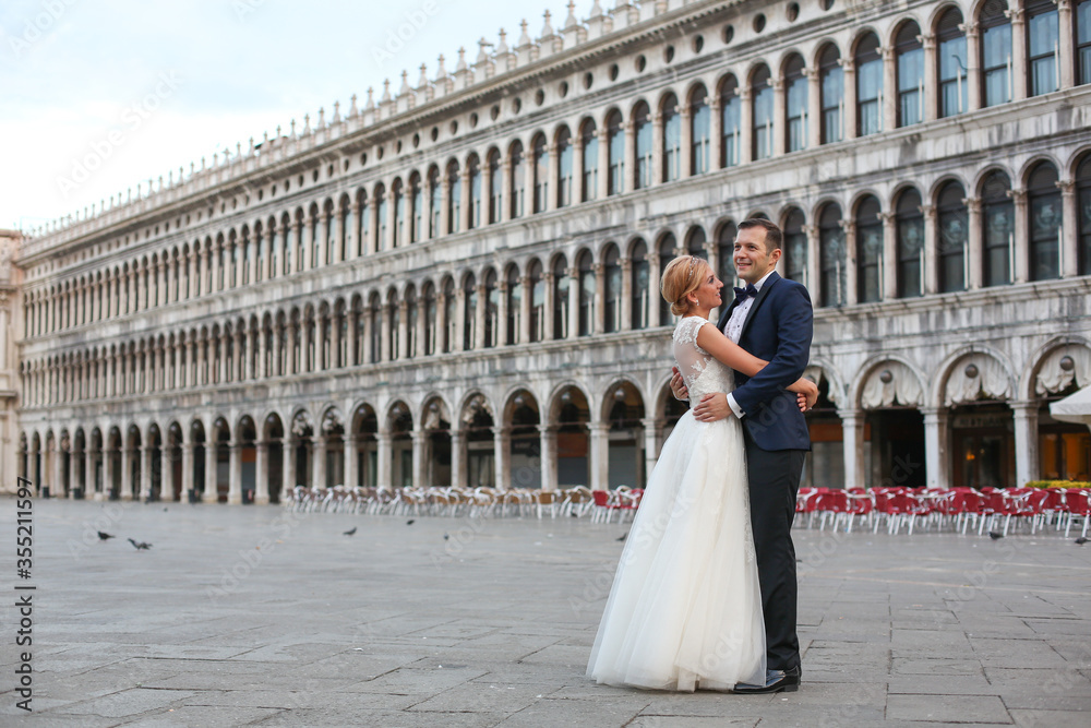Obraz premium Happy beautiful wedding couple posing in venice square