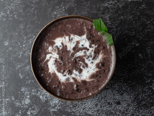 Black Glutinous Rice Porridge or Bubur Pulut Hitam in Malay with coconut milk on dark background