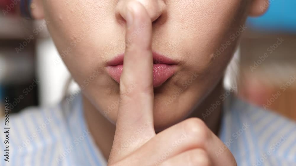 Woman asks for silence. Girl brings index finger to her lips and makes gesture calling for silence Woman asks for silence. Girl brings index finger to her lips and makes gesture calling for silence