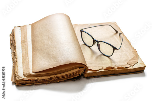 Fotografi An old, battered book with yellowed pages and reading glasses