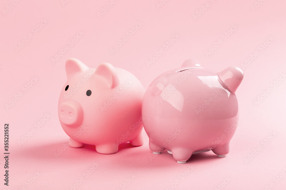 Two pink piggy banks on a pink background.