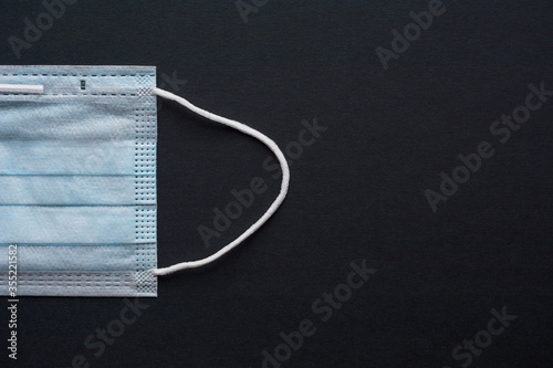Blue disposable medical face mask isolated on black background