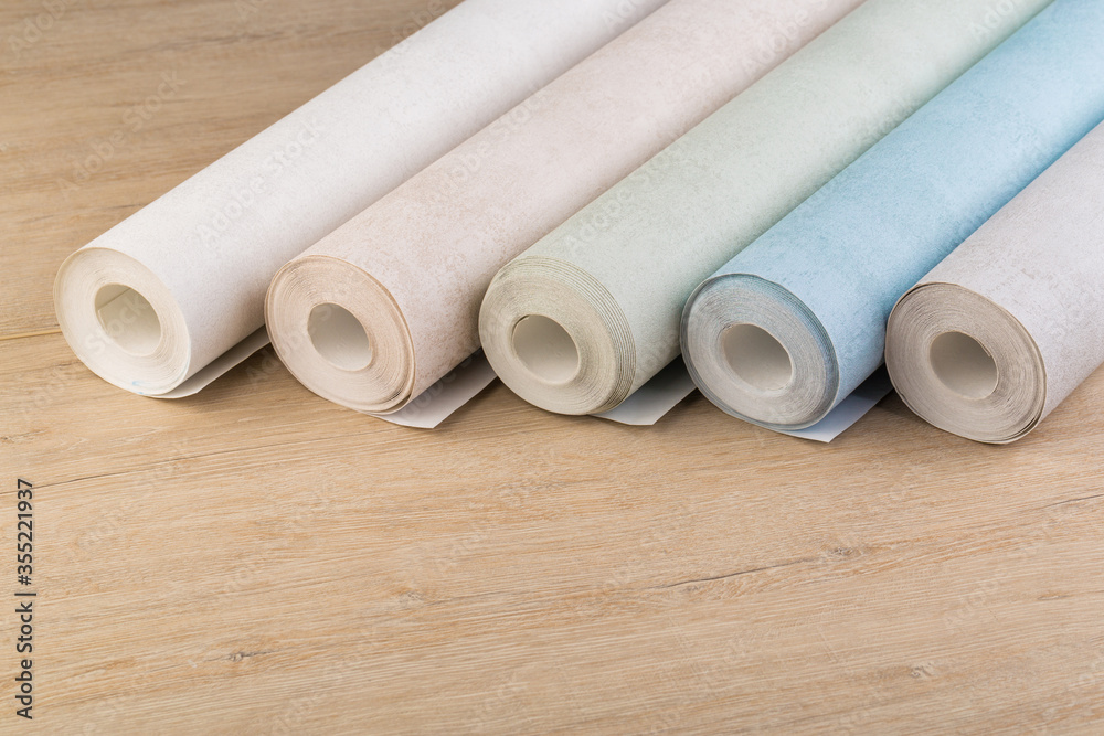 rolls of multi-colored paper wallpaper on a wooden table rolls of multi-colored paper wallpaper on a wooden table