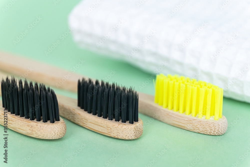 Eco natural bamboo toothbrushes on green background with waffle towel. Zero waste concept. Choice plastic free items. Selective focus Eco natural bamboo toothbrushes on green background with waffle towel. Zero waste concept. Choice plastic free items. Selective focus