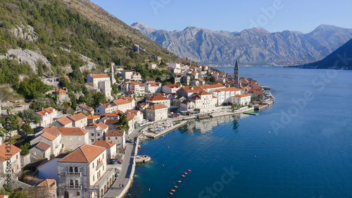 Perast Montenegro  Old medieval town featuring stone houses with red roofs  by beautiful Kotor bay  on the coast of Adriatic sea. Crystal clear rippled water surface. Sunny day. Aerial footage.