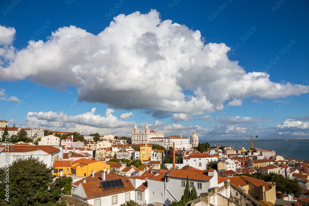 Lisbon, Portugal: Alfama district under dramatic sky on a sunny day featuring Church - Monastery of Sao Vicente de Fora and Santa Engracia (National Pantheon) as famous landmarks and attractions.