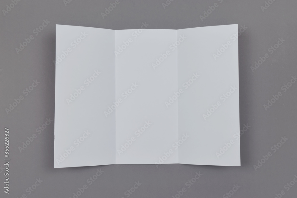 Trifold white template paper on grey background. Copy space. Top view. Trifold white template paper on grey background. Copy space. Top view.