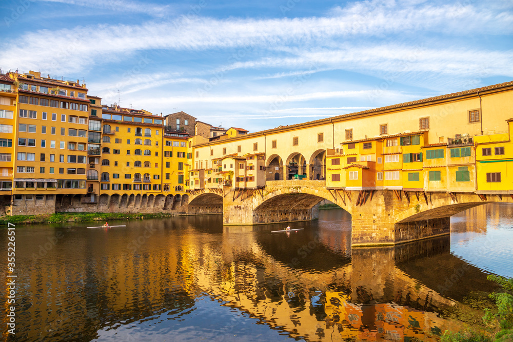 Florence Italy: Old Bridge (Ponte Vecchio) and its reflection in Arno river on a sunny morning. Famous landmark and major tourist attraction in Firenze Italia Europe.