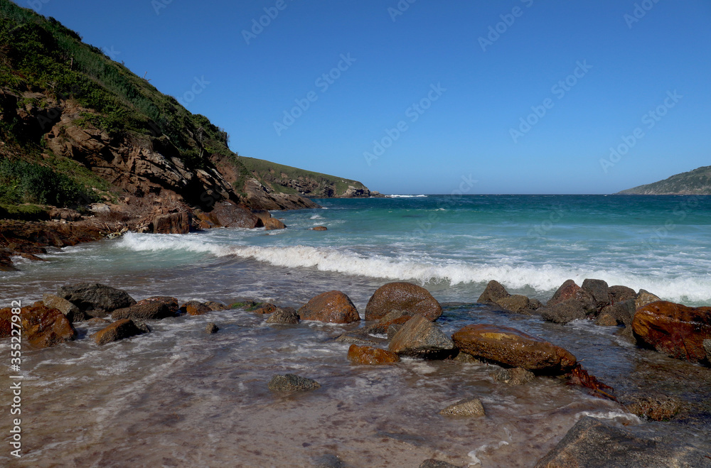 A Brazilian beach with a turquoise blue sea, a mountain and a clear blue sky without clouds.