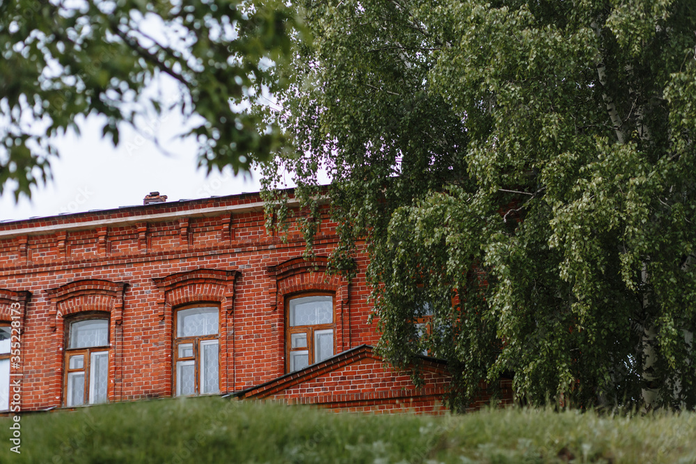 An old Russian red brick house, shot through the leaves